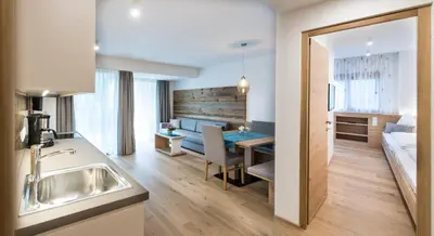 a kitchen and living room with a table and a couch at Apartm. & BB Ferienidylle Gstrein in Rablà