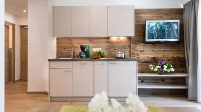 a kitchen with white cabinets and a wooden wall at Apartm. & BB Ferienidylle Gstrein in Rablà