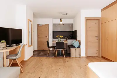 a living room with a table and chairs and a kitchen at Apartm. & BB Ferienidylle Gstrein in Rablà