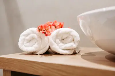 a couple of towels sitting on a table with flowers at Apartm. & BB Ferienidylle Gstrein in Rablà