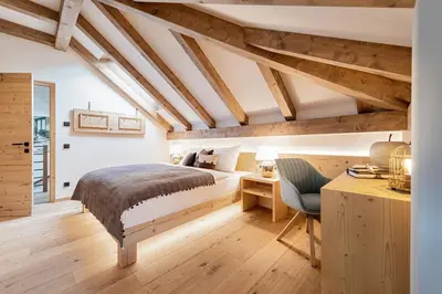a bedroom with a bed and a desk with a chair at Central Home Apartment in Ortisei