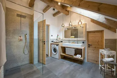 a bathroom with a shower and a sink and a washing machine at Central Home Apartment in Ortisei