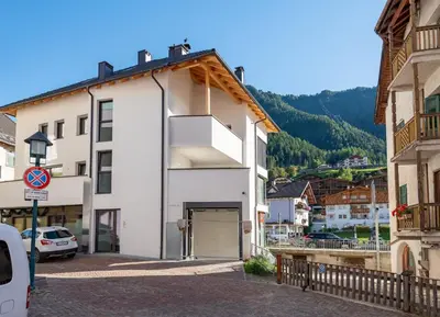 a white building with a garage in a city at Central Home Apartment in Ortisei