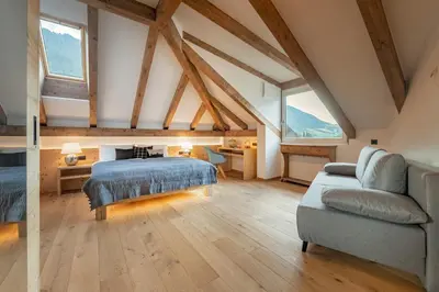 a attic bedroom with a bed and a couch at Central Home Apartment in Ortisei