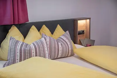 a bed with yellow and blue pillows on it at Holiday Residence Mesenhaus in Maranza