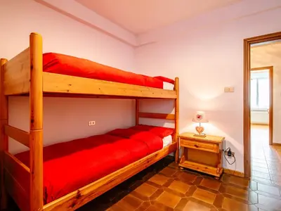 a bedroom with two bunk beds with red sheets at Apartment Mantina-1 by Interhome in Moena