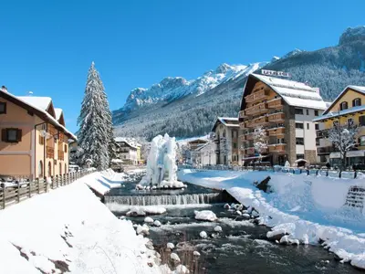 a town covered in snow with a river and buildings at Apartment Mantina-1 by Interhome in Moena