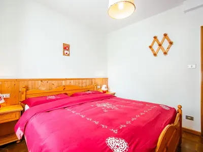 a bedroom with a bed with a pink blanket at Apartment Mantina-1 by Interhome in Moena