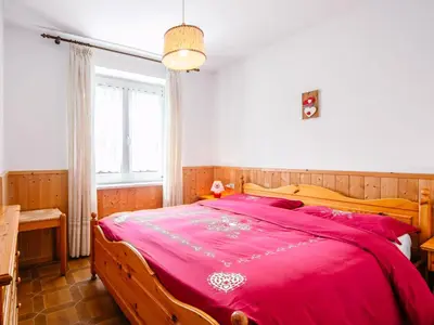 a bedroom with a large bed with a red blanket at Apartment Mantina-1 by Interhome in Moena
