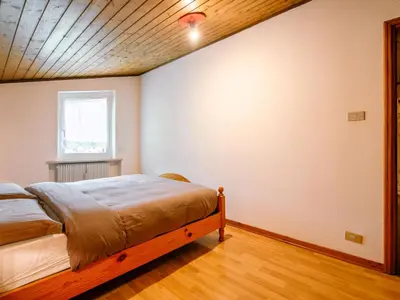 a bedroom with a large bed with a wooden ceiling at Apartment Mantina-2 by Interhome in Moena