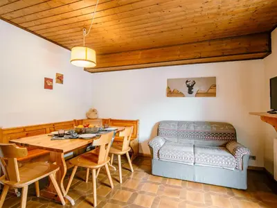 a kitchen with wooden cabinets and a table and chairs at Apartment Mantina-2 by Interhome in Moena
