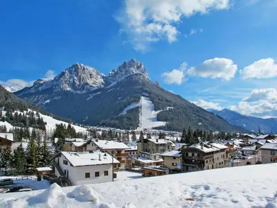 a village covered in snow with mountains in the background at Apartment Maura-2 by Interhome in Pozza di Fassa