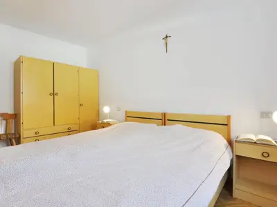 a bedroom with a large white bed and wooden cabinets at Apartment Maura-2 by Interhome in Pozza di Fassa