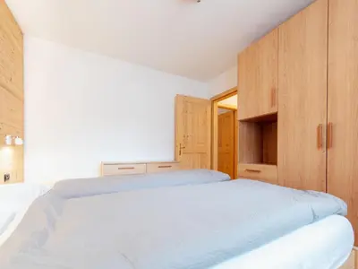 a bedroom with a bed with orange curtains and a window at Apartment Brunel - SOF773 by Interhome in Soraga