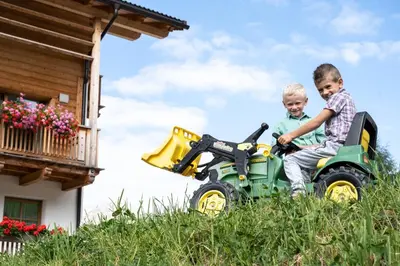 two young boys riding on a toy tractor at Unterkantiolerhof in Funes