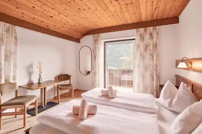 a bedroom with two beds and a table and a window at Ferienpension Zummüllerhof in Naz-Sciaves