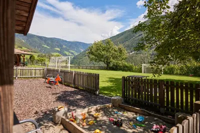 a childs play area with a fence and a playground at Ferienpension Zummüllerhof in Naz-Sciaves