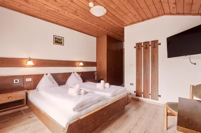 a bedroom with a bed with white sheets and a flat screen tv at Ferienpension Zummüllerhof in Naz-Sciaves