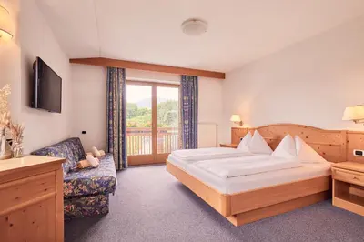 a hotel room with a bed and a chair at Ferienpension Zummüllerhof in Naz-Sciaves