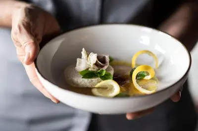 a person holding a bowl of soup with mushrooms and lemons at Hotel Pfeiss in Lana