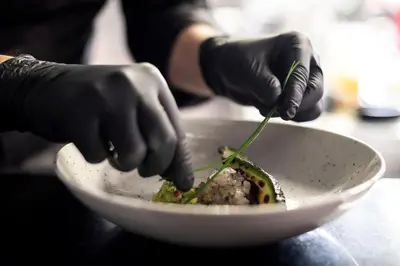 a person in black gloves preparing a dish in a bowl at Hotel Pfeiss in Lana