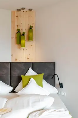 a bed with white sheets and green pillows at Hotel Pfeiss in Lana
