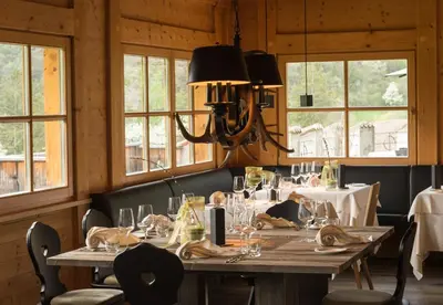 a dining room with a table and chairs and windows at Golfhotel Sonne in Siusi