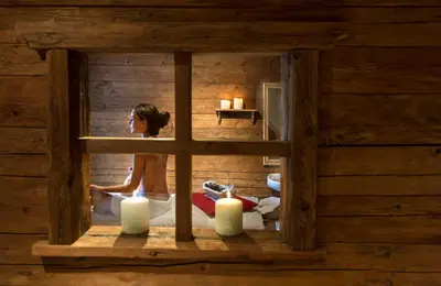 a woman is sitting in a room with candles at Golfhotel Sonne in Siusi