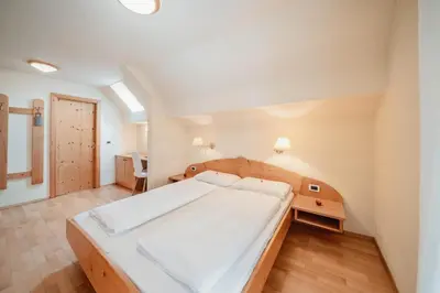 a bedroom with a large white bed in a room at Golfhotel Sonne in Siusi
