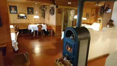 a living room with a stove in front of a table at Furggerhof in Tirolo