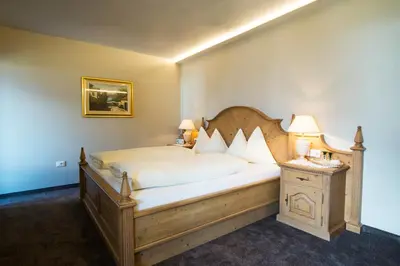 a bedroom with a large bed with a wooden headboard at Furggerhof in Tirolo