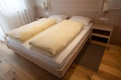 a large bed with white sheets and pillows on it at Residence Armonia in Colfosco