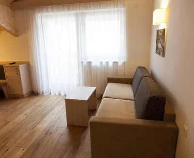 a living room with a couch and a window at Residence Armonia in Colfosco