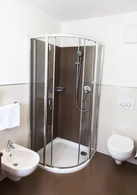 a bathroom with a shower and a toilet and a sink at Residence Armonia in Colfosco