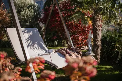 a swing in a garden with flowers in the foreground at Pension zum Burggräfler in Schenna