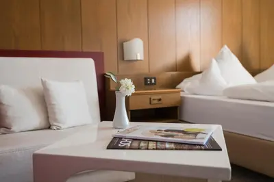a hotel room with a bed and a table with a book at Pension zum Burggräfler in Schenna