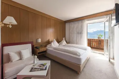a bedroom with a bed and a couch and a window at Pension zum Burggräfler in Schenna