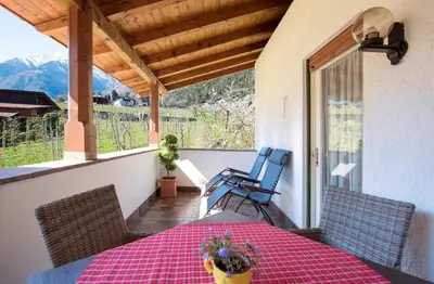 a porch with a table and chairs on a balcony at Obermaratscher Apartments Residence in Lagundo