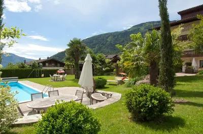 a backyard with a pool and a table and a umbrella at Obermaratscher Apartments Residence in Lagundo