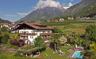 a resort with a pool and mountains in the background at Obermaratscher Apartments Residence in Lagundo