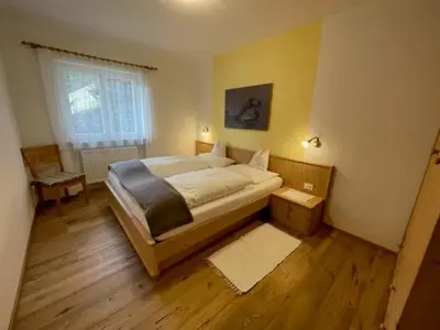 a bedroom with a large bed and a window at Schopplhof - panoramic apartments dolomites in Villnoss