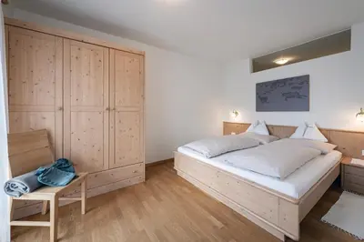 a bedroom with a large bed and a wooden cabinet at Schopplhof - panoramic apartments dolomites in Villnoss