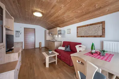 a living room with a red couch and a table at Schopplhof - panoramic apartments dolomites in Villnoss