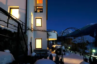 a building with lights in the snow at night at Art Apartment Schatzer in Funes