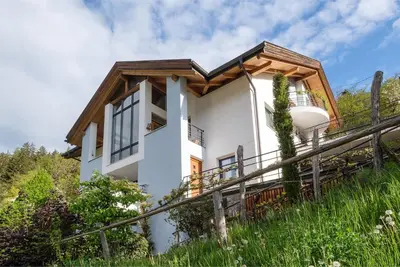 a white house with a wooden roof at Art Apartment Schatzer in Funes