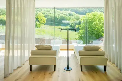 a living room with two chairs and a large window at Hotel Tenz in Montagna