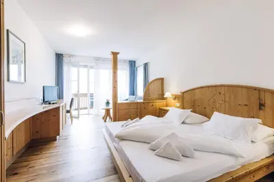 a bedroom with a large bed with a wooden headboard at Hotel Tenz in Montagna