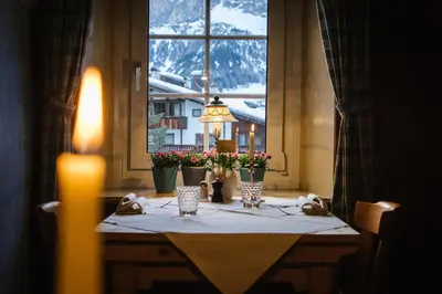 a bedroom with a white bed and a wooden door at Berghotel Ladinia in Corvara in Badia