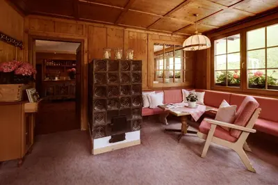 a dining room with tables and green curtains and windows at Berghotel Ladinia in Corvara in Badia
