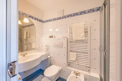 a white bathroom with a sink and a toilet at Schlosshotel Aehrental in Caldaro